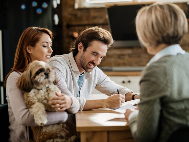 Happy,Man,Signing,A,Contract,While,Being,With,His,Wife